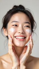 Smiling japanese woman applying face cream. Asian female with perfect skin applies moisturizer to the face skin. Healthy skincare, beauty treatment, cosmetology. Spa, wellness, beauty.