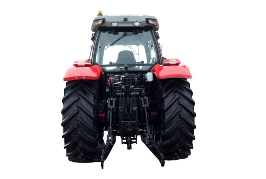 The red farm tractor stands prominently, viewed from the back, highlighting its large tires and agricultural machinery. It is parked in an open field, reflecting a typical day on the farm.