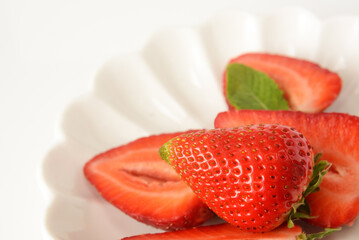 Light background with strawberry berry on white saucer, selective focus