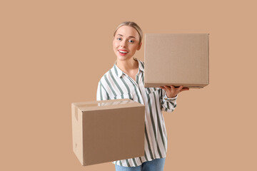 Young woman with parcel boxes on beige background