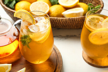 Fototapeta premium Glasses of lemon ice tea with mint and citrus fruits on white background, closeup