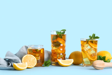 Glasses of lemon ice tea with mint and citrus fruits on blue background