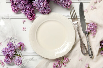 Beautiful table setting with lilac flowers on white background