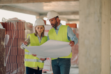 Construction workers examining blueprint on building site