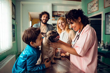 Family with dog visiting smiling female veterinarian at animal clinic
