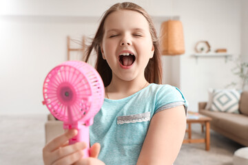 Cute girl with blowing mini fan at home, closeup
