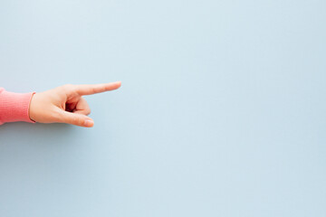 Hand in pink is pointing empty space on the right side by finger  isolated on pastel blue background	