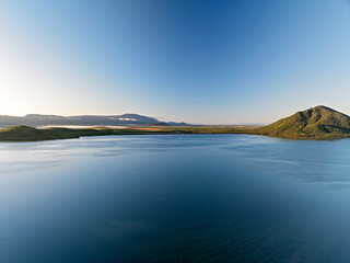 Aerial panorama of Sinclair Bay with forested hills and smooth water surface.