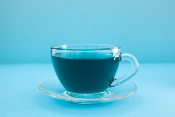 Thai anchan blue tea in the glass cup on the light blue background, abstract creative blue card with beverages 