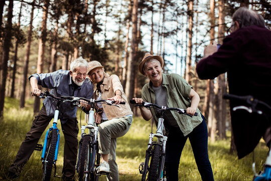 Group of senior friends cycling together through forest trail