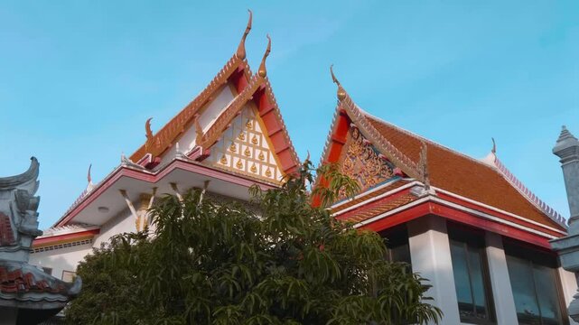 Traditional Thai Buddhist temple with beautiful red tiled roof with magnificent chofas in Thai architectural style. Shot in motion