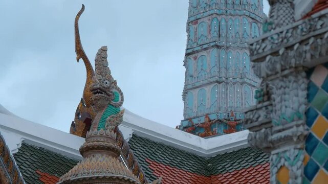 Skillfully crafted ornate golden and blue serpent-like Chofahs on traditional Thai style temple roofs in Bangkok, Thailand. Shot in motion