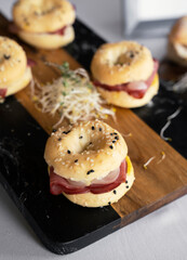Gourmet catering service for social events. Closeup view of mini pastrami bagels displayed in a dark marble board