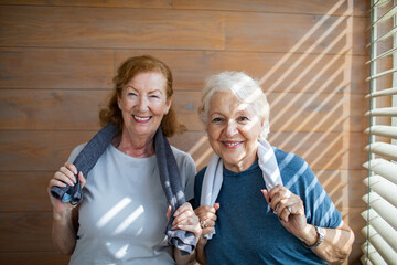 Active senior lesbian couple smiling after workout with towels around necks