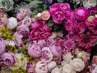 array lifelike artificial flowers fills arrangement, featuring various shades pink and purple. collection showcases peonies, roses, and more, ideal for decor. close-up.