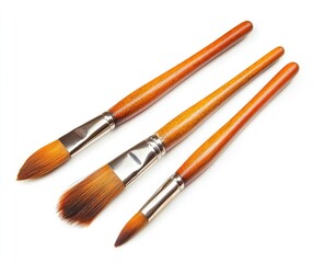 Fototapeta premium Three paintbrushes of varying sizes, with wooden handles and light brown/orange color, are arranged diagonally against a white background