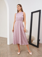 Stylish woman in casual polka dot dress posing in modern interior with arc elements