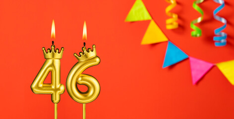 Number 46 birthday candle on an orange background with pennants