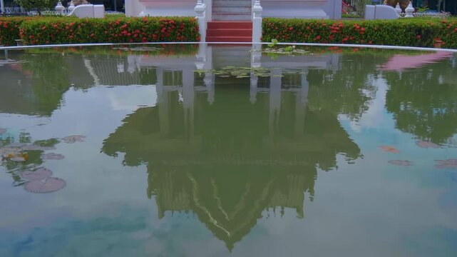 Reflecting in the water a traditional Thai pavilion with a statue of Goddess Uma Devi (Mother Uma) stands in the garden of a Crocodile farm in Samut Prakan