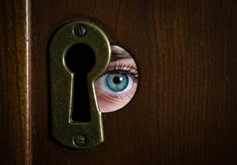 Close Up Of A Blue Eye Peeking Through A Keyhole On A Wooden Door Photo