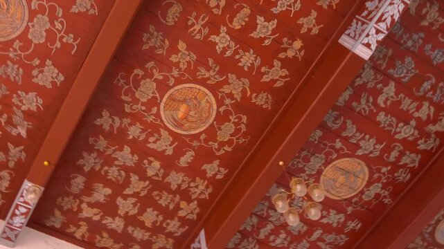 A red color intricately decorated with traditional Thai style floral patterns ceiling of Wat Mai Chai Wichit Buddhist temple in Ayutthaya, Thailand
