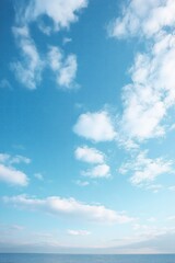 Obraz premium Bright blue sky with scattered white clouds over calm ocean horizon creating a peaceful and serene atmosphere
