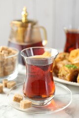 Tasty Turkish tea served with sweets on white marble table, closeup