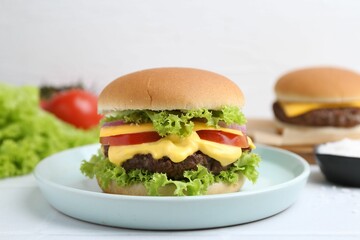 Tasty cheeseburger with lettuce and tomatoes on white table, closeup