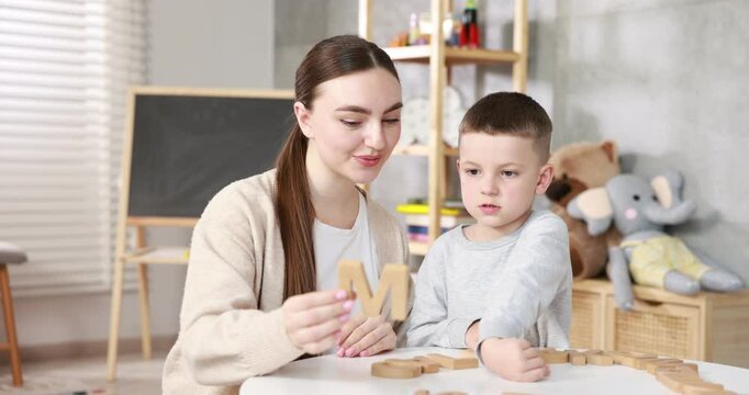 Dyslexia. Mother and her son learning letters at table indoors