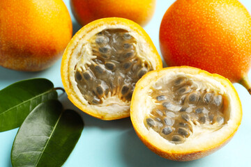Ripe yellow passion fruits and leaves on light blue background, closeup