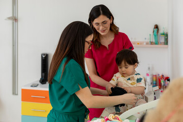 Pediatrician assisting baby with mother in doctor's office