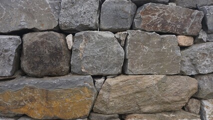 A rustic stone wall built with weathered rocks, evoking timeless strength and natural charm