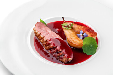 Grilled fillet beef steak or grilled beef medallion with baked pear and sauce in plate isolated on white background. Meat dishes, top view, close up