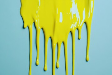 Dripping yellow paint on light blue surface