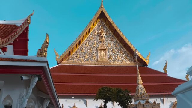 Royal monastery with amazing traditional Thai style gold carving on the walls and roof with Garuda bas-relief and serpent-like chofahs on the edges. Shot in motion