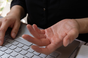 A businesswoman in front of a computer, palm of her hand facing up