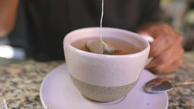hand of an unknown man filtering tea.