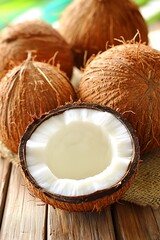 Coconuts on rustic wooden surface, open revealing white flesh and water