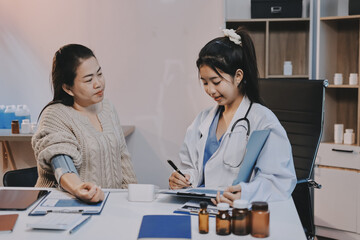 Fototapeta premium Doctor using sphygmomanometer with stethoscope checking blood pressure to a patient in the hospital.