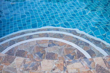 The stairs leading down to the swimming pool are curved.