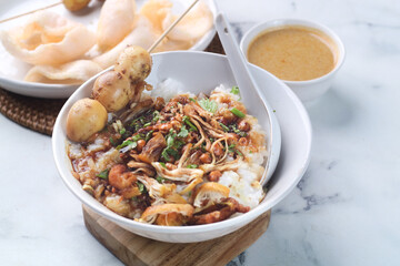 a bowl of chicken porridge with quail eggs satay, warm food
