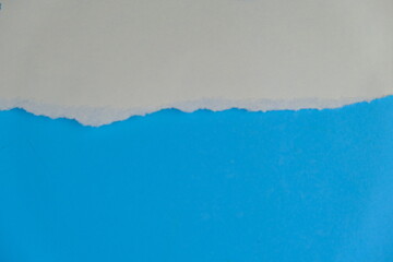 torn hole in white paper revealing a blue background. Space for text.
