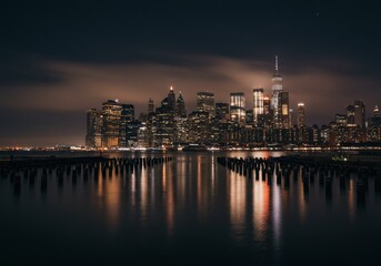 Naklejka premium Photo of a City Skyline at Night with Lights Reflected in Still Water