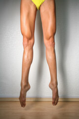 Cropped shot of woman's long legs, while jumping with fully extended with pointed toes. Unrecognisable woman showing her sporty muscular legs, dancer, ballerina, gymnast  jump