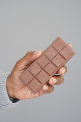 Chocolate bar held in hand against a neutral background