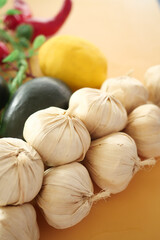 Fresh garlic bulbs and colorful vegetables on kitchen table