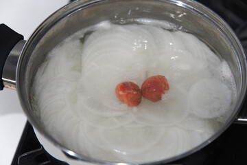スライスした大根と梅干しを煮る様子