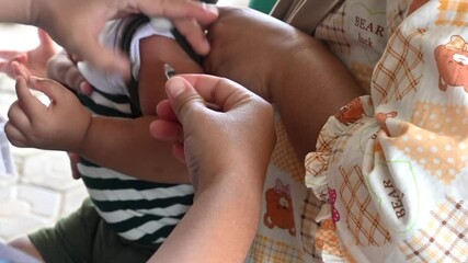 inject a vaccine into a baby. inject measles vaccines into a baby's arm. basic immunization of a child in Indonesia. - Powered by Adobe