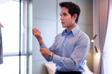 Fototapeta premium Asian Man Adjusting Shirt Sleeves Getting Ready For Work Fashionable Young Adult Professional Attire Concept Luxury Watch Accessory