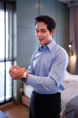 Asian Man Adjusting Watch Before Work Preparing Himself With Elegance Getting Ready In Bedroom...